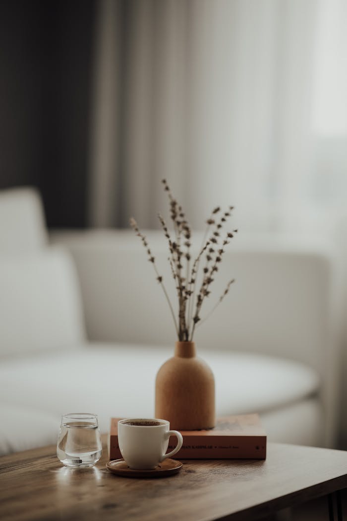 Warm minimalist home interior with a coffee cup, book, and vase on a wooden table.