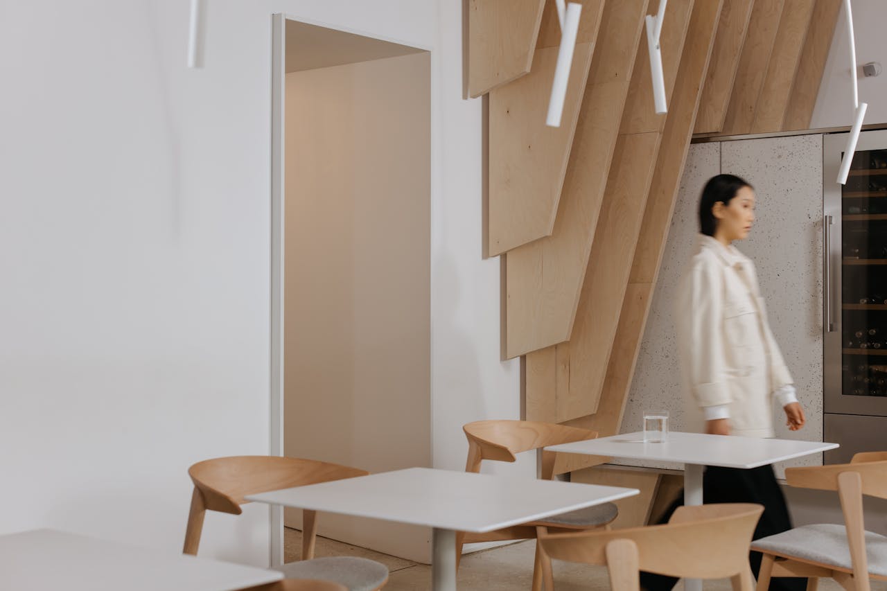 A woman walking through a modern Japandi-style interior featuring minimalist wooden decor and neutral tones.