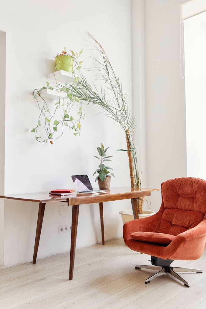 Bright and stylish home office setup with a red chair, wooden desk, and indoor plants.